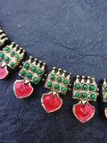 terracotta necklacet with red heart and green gemstone details on a dark background