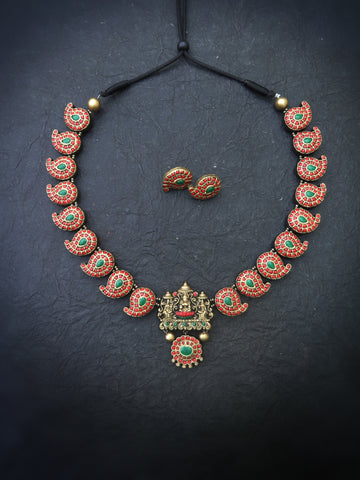 Terracotta necklace with green and red stones on a dark background