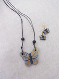 Butterfly Terracotta  necklace and earrings on a light gray fabric background