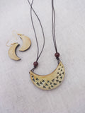 Crescent-shaped Terracotta  necklace and earrings on a textured fabric background