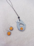 Bird-shaped Terracotta pendant and flower earrings on a light gray background