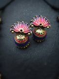 Pair of terracotta earrings with floral design on a dark background