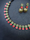 Terracotta necklace and earrings with green and red accents on a dark background