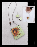 Necklace with sunflower Terracotta pendant and matching earrings on a textured surface.