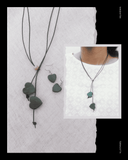 Green heart-shapedTerracotta  jewelry set including necklace and earrings on a textured white background.
