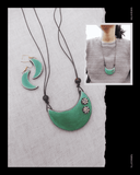 Green crescent-shaped Terracotta necklace and earrings on a textured white background