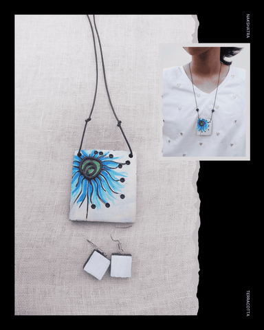 Jewelry set with a Terracotta pendant and earrings on a textured white surface.