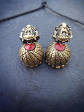 Pair of gold terracotta earrings with red stones on a dark blue fabric background