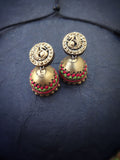 Pair of gold terracotta earrings with intricate designs on a dark blue background