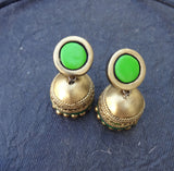 Gold terracotta earrings with green stones on a dark blue textured background