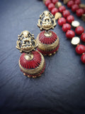 Red and gold  terracotta earrings on a dark surface with red beads in the background