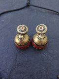 Pair of gold and red terracotta  terracotta earrings on a blue fabric background