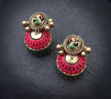Pair of ornate terracotta  earrings with pink and gold design on a dark background