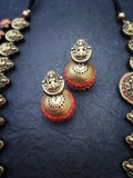Pair of gold and red  terracotta earrings on a dark blue background
