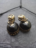 Pair of black and gold terracotta  earrings on a textured gray surface