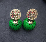 Green earrings with gold and red  terracotta accents on a dark textured background