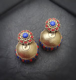 Pair of gold  terracotta  earrings with blue and red accents on a dark surface