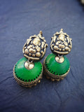 Green and gold terracotta earrings on a dark blue background