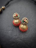 Pair of gold and red terracotta earrings on a dark textured surface