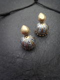 Pair of gold and silver terracotta earrings on a dark textured surface