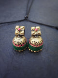 Pair of gold and green terracotta  earrings with pink stones on a dark fabric background
