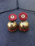 Pair of terracotta earrings with red and gold design on a blue background