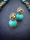 Turquoise terracotta earrings with gold accents on a dark background