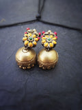 Pair of gold terracotta earrings with colorful stones on a dark fabric background