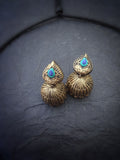 Pair of gold terracotta earrings with turquoise stones on a dark fabric background