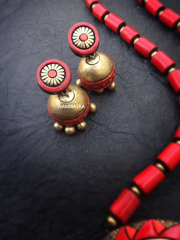 Brass and red terracotta earrings on a dark surface